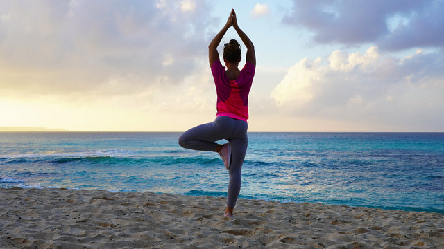 girl do yoga near the ocean while watching the sunset. yoga assans on a tropical beach against a bright orange sunset sky. harmony with nature. sports figure