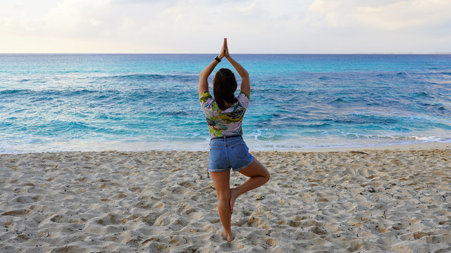 girl do yoga near the ocean while watching the sunset. yoga assans on a tropical beach against a bright orange sunset sky. harmony with nature. sports figure