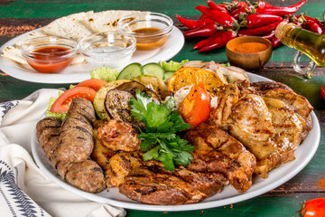Different types of meat and vegetables shot on a wooden background