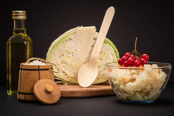 Fermented cabbage with herbs and spices in glass bowl on the black background