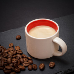 Cup of coffee and coffee beans on black background
