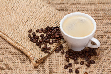 Cup of coffee and coffee beans on sackcloth