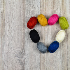 Heart of colored skeins of yarn for knitting on a wooden background.
