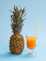 Fresh tropical fruits and glass of juice on blue background.