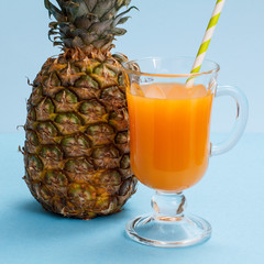 Fresh tropical fruits and glass of juice on blue background.