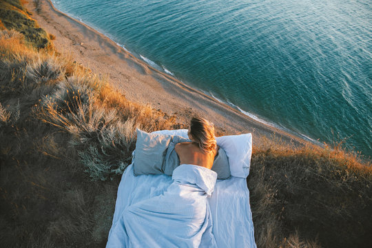 Woman enjoying view on beach landscape while relaxing in bed in sunset on the edge of Earth
