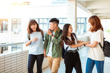 Group of happy students walking along the corridor at college