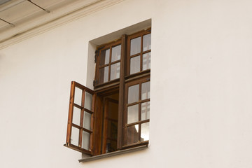 open wooden brown window on a white plastered wall from the outside. window outside the house. copyspace. double-leaf window with window leaf, European style