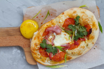 pizza with ingredients: dough, tuna, tomato sauce, egg and oregano. Small pizza with tomatoes, olives, mozzarella cheese and fresh Basil on a wooden Board, close-up. the concept of fast food.