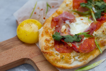 pizza with ingredients: dough, tuna, tomato sauce, egg and oregano. Small pizza with tomatoes, olives, mozzarella cheese and fresh Basil on a wooden Board, close-up. the concept of fast food.
