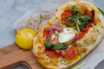 pizza with ingredients: dough, tuna, tomato sauce, egg and oregano. Small pizza with tomatoes, olives, mozzarella cheese and fresh Basil on a wooden Board, close-up. the concept of fast food.
