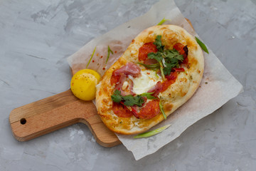 pizza with ingredients: dough, tuna, tomato sauce, egg and oregano. Small pizza with tomatoes, olives, mozzarella cheese and fresh Basil on a wooden Board, close-up. the concept of fast food.