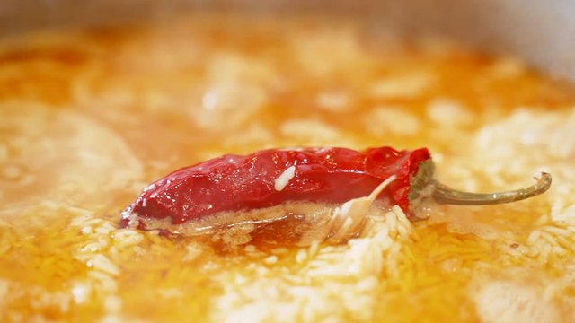Uzbek national dish pilaf in a cauldron, red chili pepper, cooking, rice. Chili pepper close up.