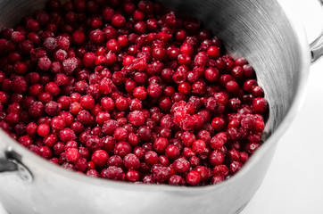 Frozen lingonberries in a saucepan for cooking compote.