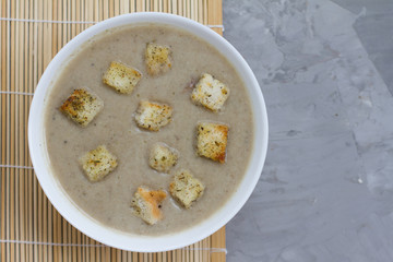 mushroom soup with breadcrumbs in a white plate. soup-puree on a gray background. food for lunch. liquid food. dish for cafes and restaurants. the concept of the menu. the view from the top. 