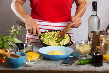 Woman cooking pasta with white cream sauce at home in the kitchen