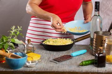 Woman cooking pasta with white cream sauce at home in the kitchen
