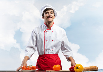 Young male chef standing near cooking table