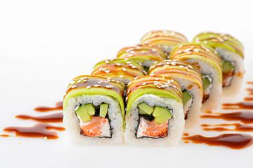 Uramaki tori sushi, a set of green rolls with sesame seeds and unagi sauce isolated on white. Eight pieces of sushi.