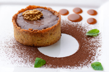 Chocolate creme brulee with cocoa powder, walnuts and mint leaf. Traditional French vanilla cream dessert.