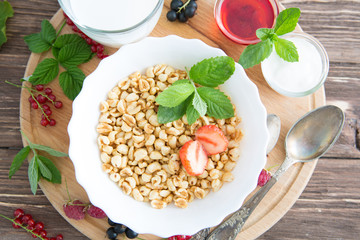 Healthy breakfast. Oatmeal with berries and honey. Healthy tasty breakfast of muesli with strawberries, raspberries, black currants and red currants.
