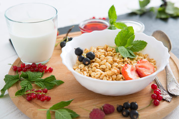 Tasty cornflakes with berries on wooden background Healthy tasty breakfast of muesli with strawberries, raspberries, black currants and red currants.