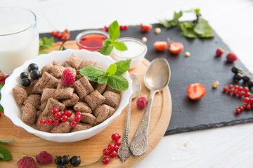 healthy breakfast cereal with fruit on the summer table Healthy tasty breakfast chocolate square pads with strawberries, raspberries, black currants and red currants.