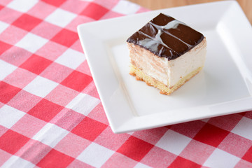 Chocolate souffle with thick chocolate ganache glaze served on a white plate on red plaid background
