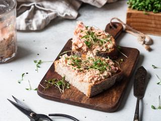 Healthy toasts with salmon pate and fresh green sprouts on yeast-free bread on wood cutting board...