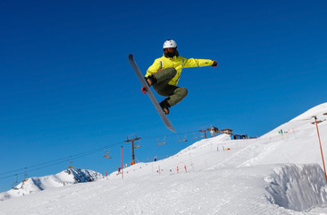 Naklejka na ściany i meble Male snowboarder against the blue sky. Livigno, Italy