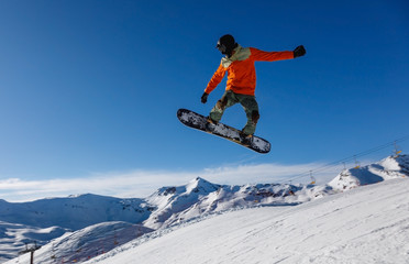 Naklejka na ściany i meble Snowboarder jumps in snow park in the snowy mountains in Livigno, Italy