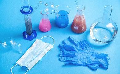 Science glassware with colored liquid and gloves.