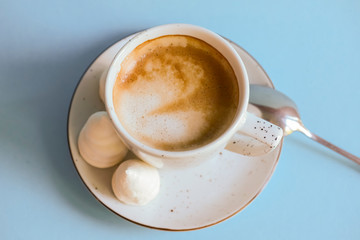 A cup of coffee latte or americano in a white cup isolated on light pastel blue background.