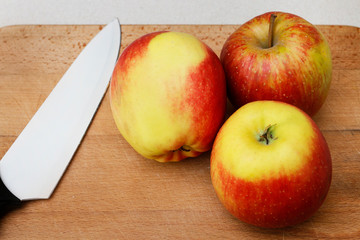 Naklejka na ściany i meble Red apples and a knife on wooden board.