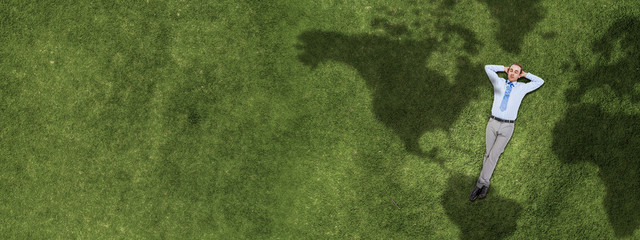 Relaxing businessman on grass . Mixed media