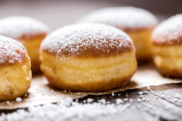 Close-up of donuts (Berlin pancakes) dusted with powdered sugar served on a rustic wooden table - 319646128