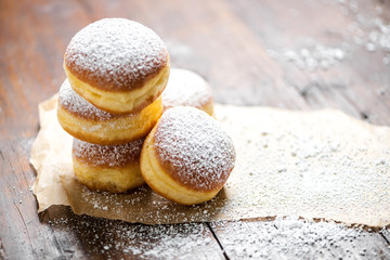Close-up of donuts (Berlin pancakes) dusted with powdered sugar served on a rustic wooden table - obrazy, fototapety, plakaty