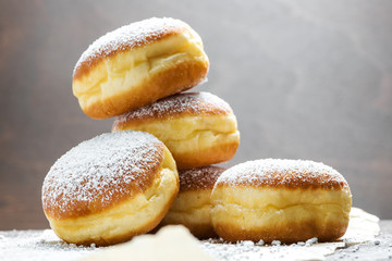 Close-up of donuts (Berlin pancakes) dusted with powdered sugar served on a rustic wooden table - obrazy, fototapety, plakaty