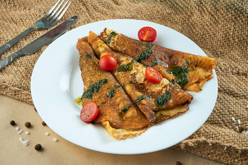 Close up view on tasty French crepes stuffed with spinach in a white ceramic plate. Food flat lay