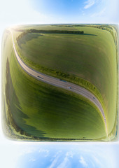 Abstract aerial view in the form of cube of a landscape while traveling by car on an highway in the middle of a green agricultural field with grass with a blue sky. Ecology and the environment.
