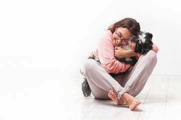 Girl hugs her dog. On a light background. Place for text.