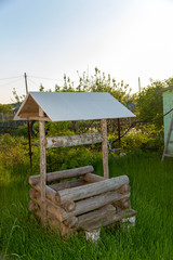 Decorative wooden well in the garden. Outbuildings in the garden of a country house. Design of the infield. 