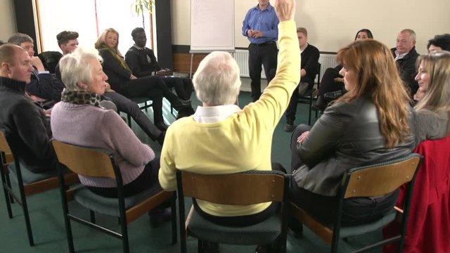 Answering a Question during a group meeting - Leader writing on a flipchart in a seminar setting. Group of people. Crane Shot