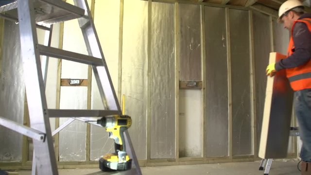 Builder installing insulation panels into a new build on a construction site.