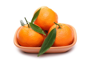 Mandarins with leaves in clay bowl isolated on white background