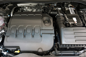 The engine of a modern luxury car, the cover protects the engine from dust and dirt. The concept of quality service and repair of a modern luxury car.