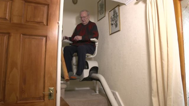 Senior Citizen man coming down the stairs on a Stairlift inside his home