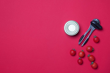 opener , tomato and tin can on red colored paper background with copy space