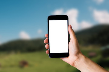 Mockup image of hand holding white mobile phone with blank white green nature background.