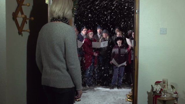 Carol Singers at Christmas Singing outside home front door -Snowing - View from Inside, Crane Shot - Stock Video Clip footage
